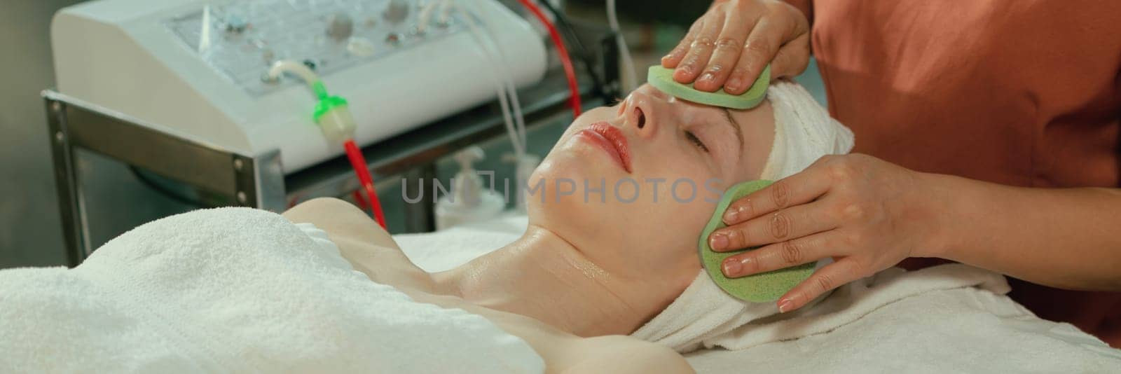 Attractive caucasian woman receive electrical facial treatment. Beautiful girl lies on spa bed while having medical treatment from professional doctor from medical spa center. Tranquility.
