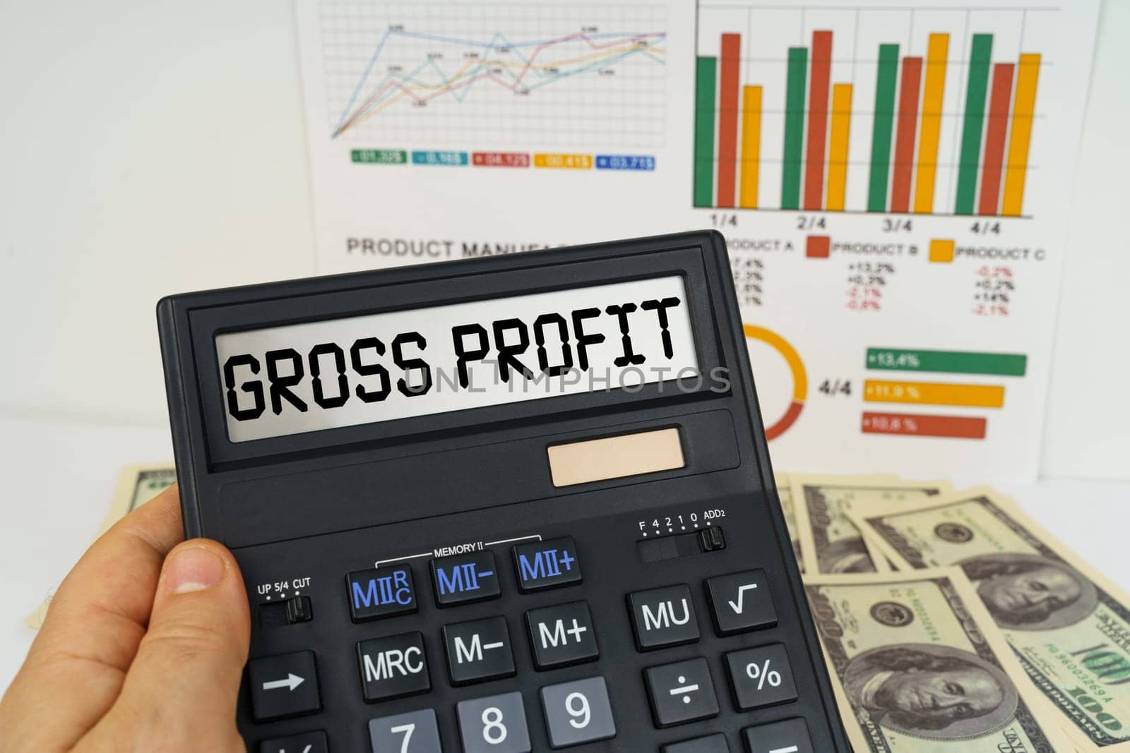 Business concept. On the table there are financial reports, dollars, in the hands of a calculator with the inscription - gross profit