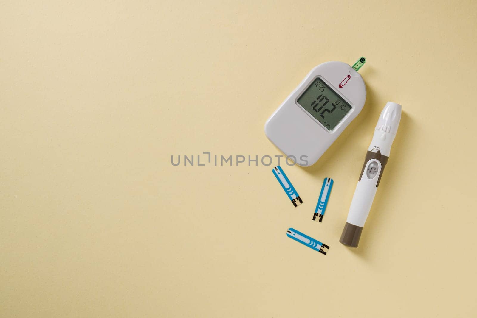 Top view of glucometer, lancet pen and strips on yellow background. diabetes test kit