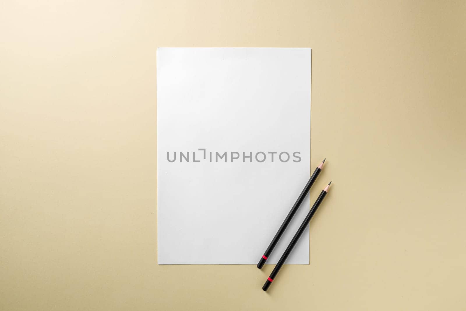 Blank white paper and black pencil on yellow background