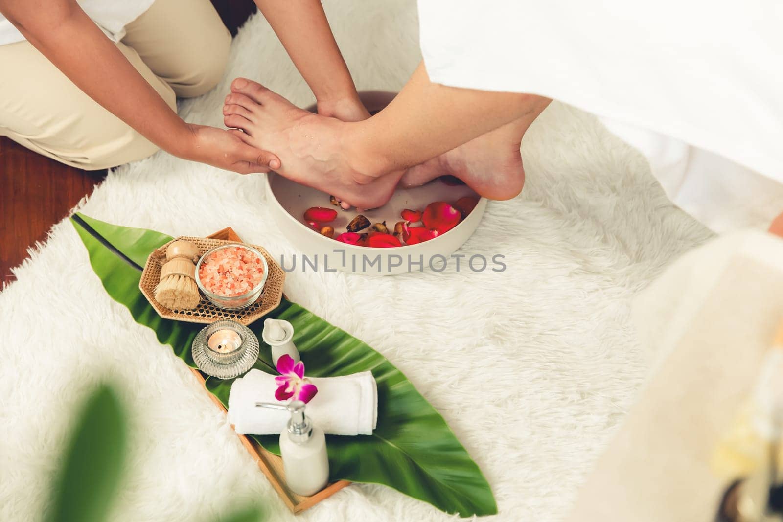 Man indulges in blissful foot massage at luxurious spa salon while masseur give reflexology therapy in gentle day light ambiance resort or hotel foot spa. Quiescent
