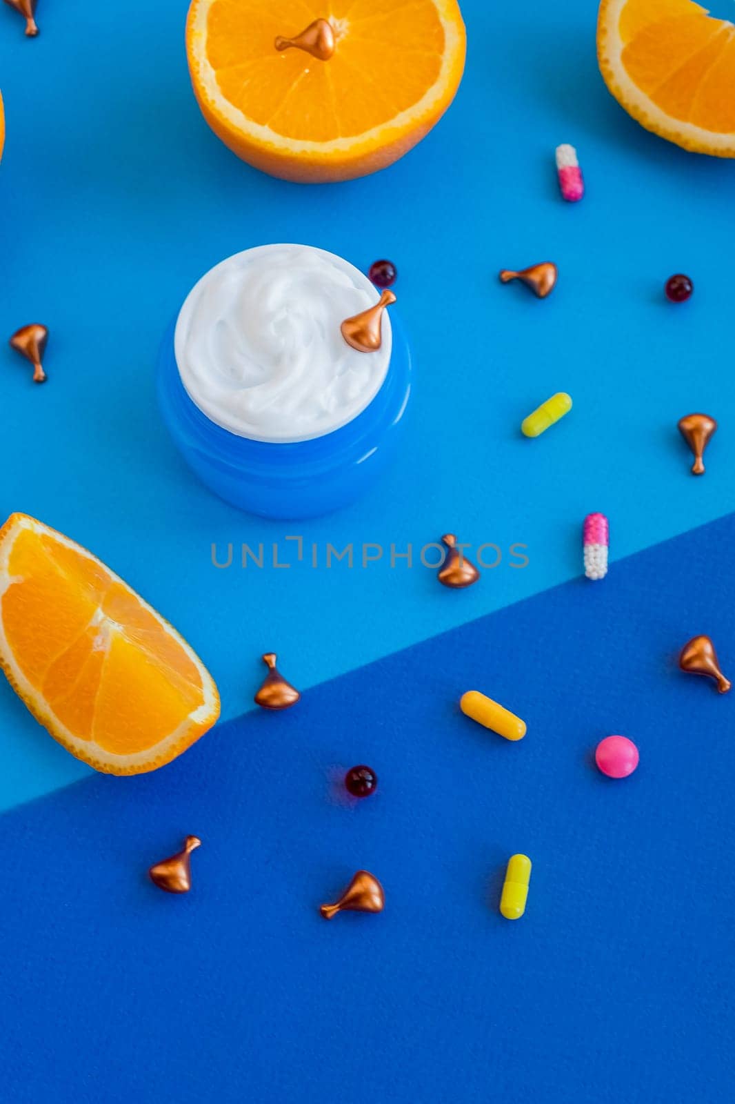 bright flatlay composition with oil, pills, vitamins, capsules, face cream, citrus and oranges on blue background. Concept beauty natural vitamin cosmetic product, skin care. beauty care aroma therapy by YuliaYaspe1979
