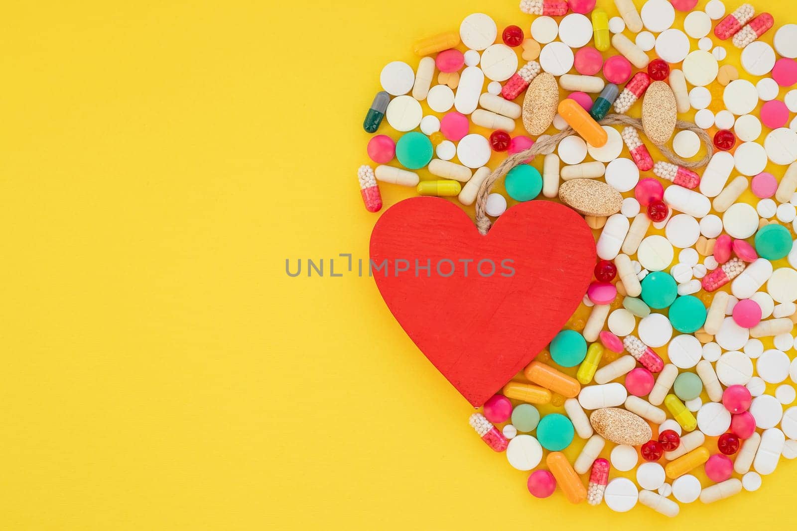 Heart and colorful pills on yellow background.HEART ATTACK concept. medical pills.Pharmaceutical medicament,health care. Pharmacy theme.Copy space by YuliaYaspe1979