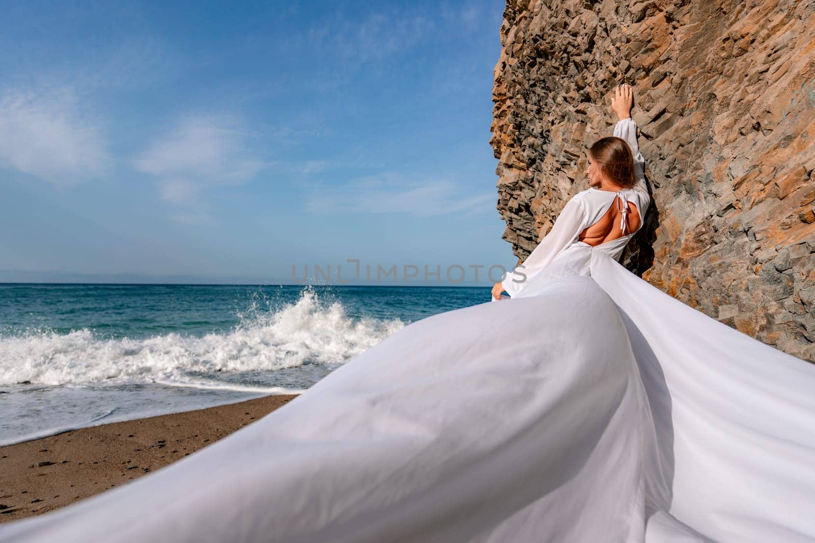 Woman beach white dress flying on Wind. Summer Vacation. A happy woman takes vacation photos to send to friends. by Matiunina