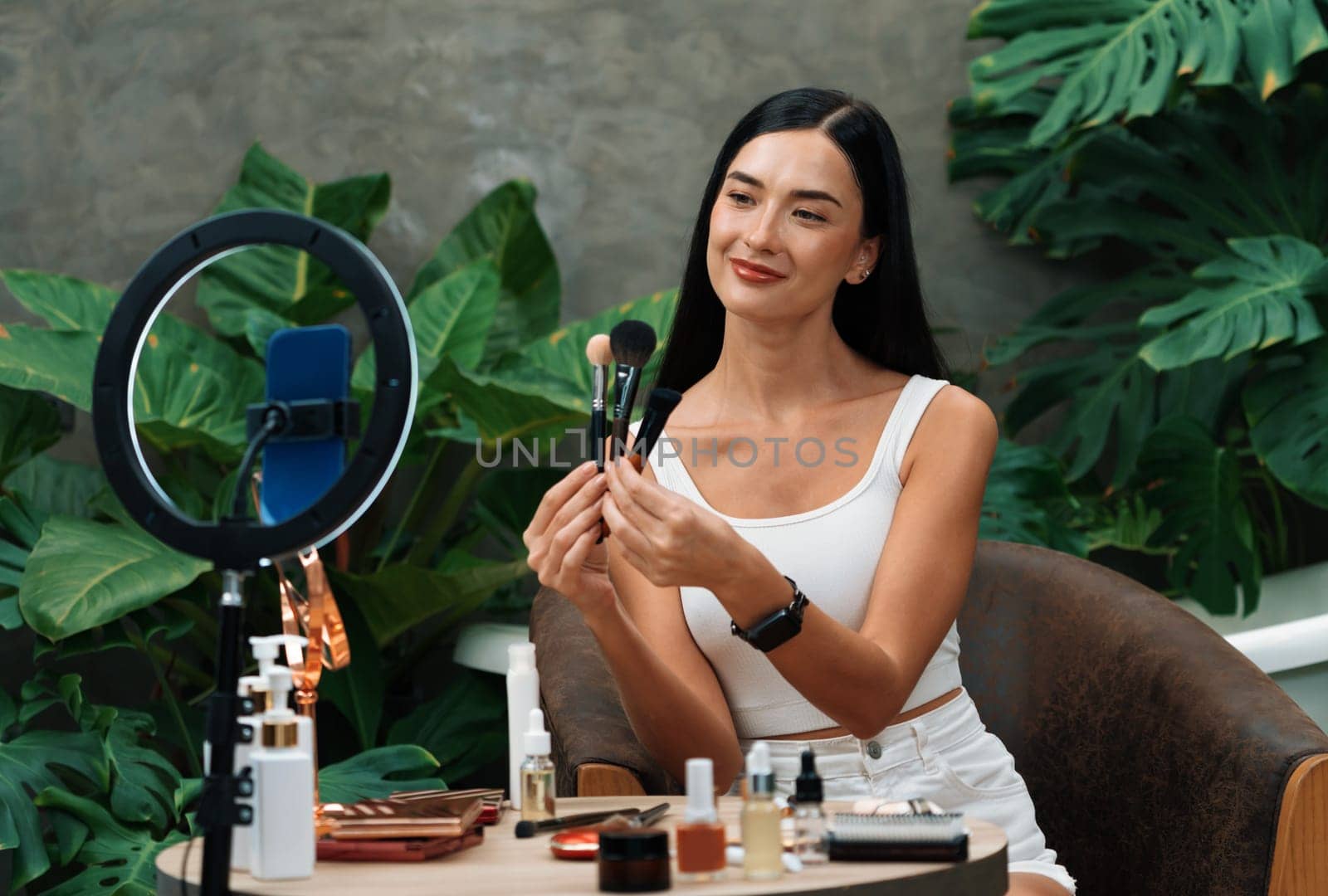 Young woman making natural beauty and cosmetic tutorial on green plant garden video content for social media. Beauty celebrity blogger showing how to beauty care to audience or followers. Blithe