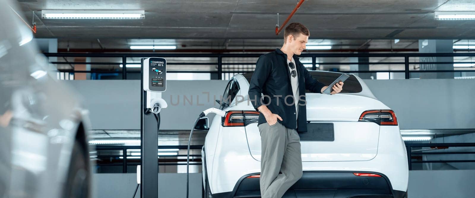 Young man travel with EV electric car to shopping center parking lot innards by biancoblue