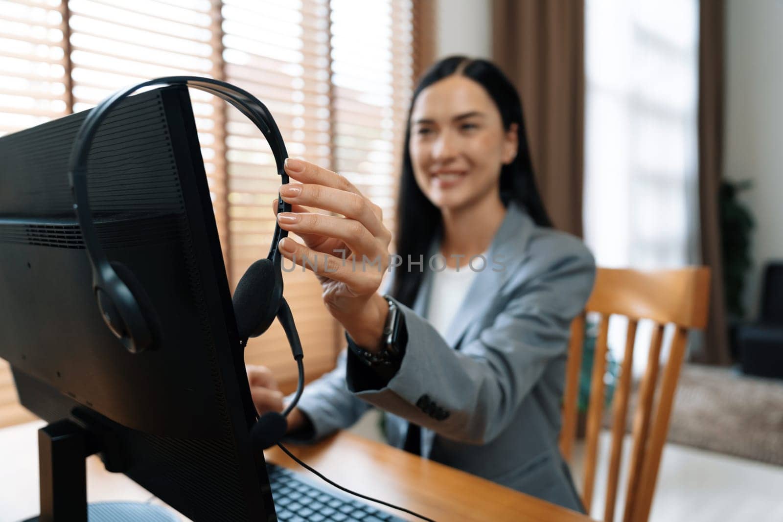 Female call center operator or customer service helpdesk staff working on workspace while talking on the headset to provide assistance for customer. Professional modern business service. Blithe