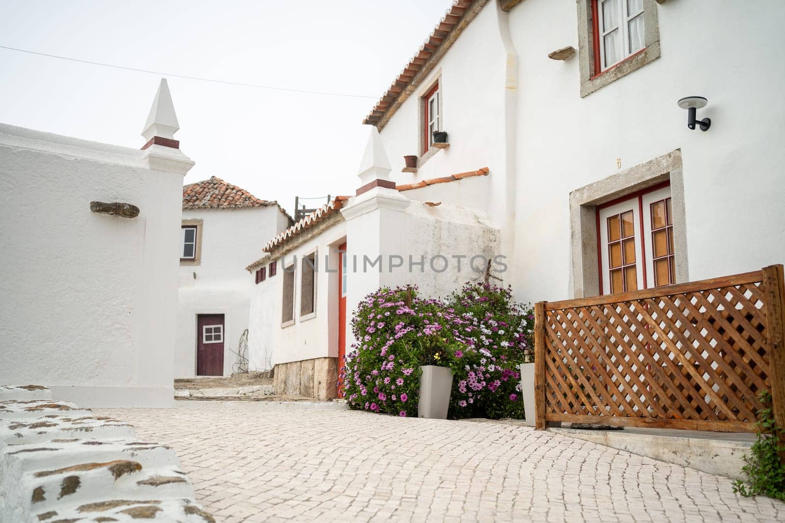 Exterior of beautiful white two-storey houses in town. Typical empty street along white buildings in city. Wooden flower fence and residential buildings in Portugal city.