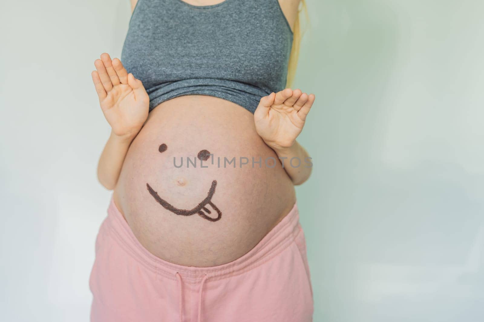 Adorable moment as a son adds a touch of joy to his mother's pregnancy, playfully drawing a funny face on her baby bump, creating cherished memories by galitskaya