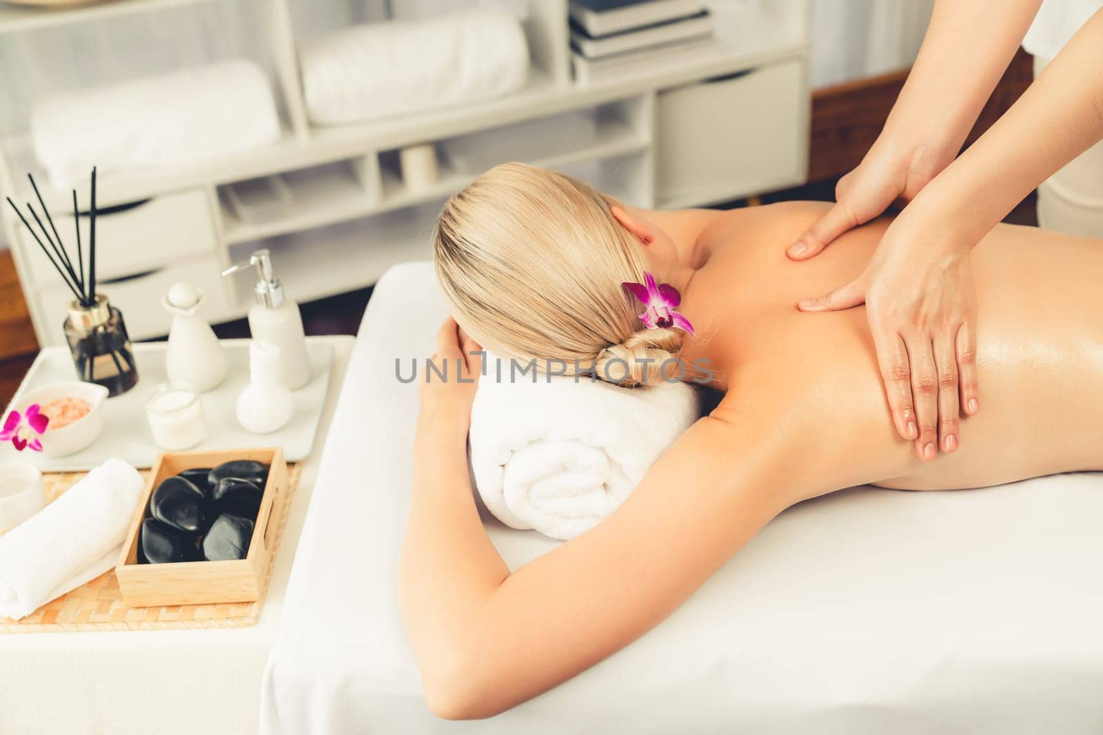 Caucasian woman customer enjoying relaxing anti-stress spa massage and pampering with beauty skin recreation leisure in day light ambient salon spa at luxury resort or hotel. Quiescent