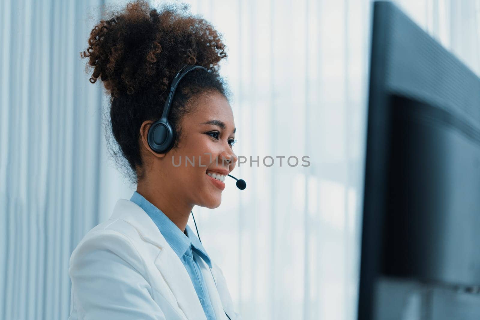 African American businesswoman wearing headset working in office to support remote crucial customer or colleague. Call center, telemarketing, customer support agent provide service on video call.