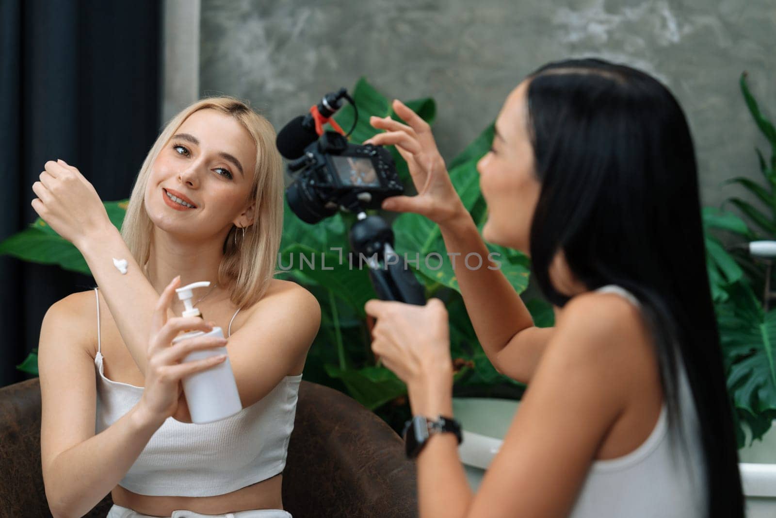 Two beautiful content creator making natural beauty and cosmetic tutorial on green plant garden video. Beauty blogger showing how to beauty care to social medial audience using selfie stick . Blithe