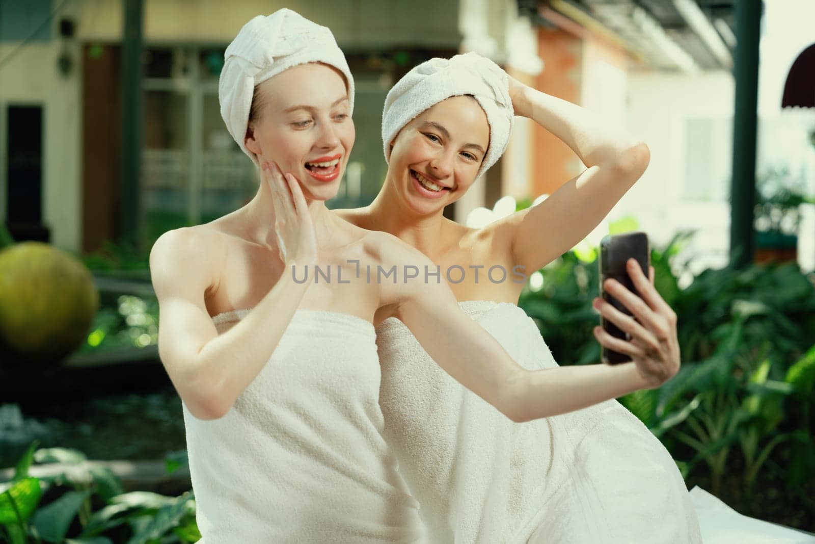 Couple of beautiful women in white towel taking a photo at outdoor. Tranquility. by biancoblue