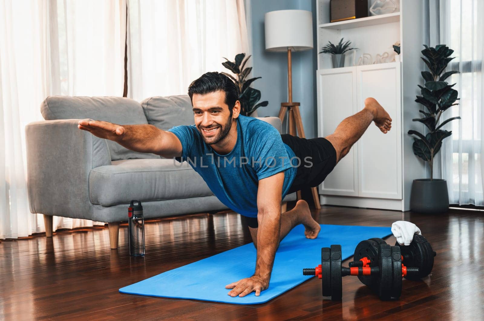 Flexible and dexterity man in sportswear doing reverse gaiety yoga position by biancoblue