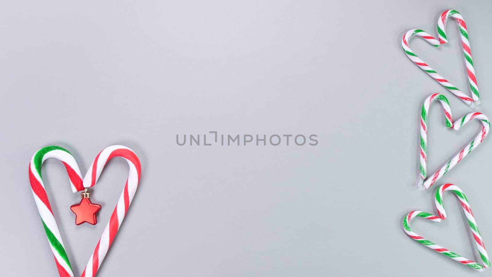 Christmas candy cane, golden and red stars, small and big candies on grey background. Christmas composition. Top view, flat lay.