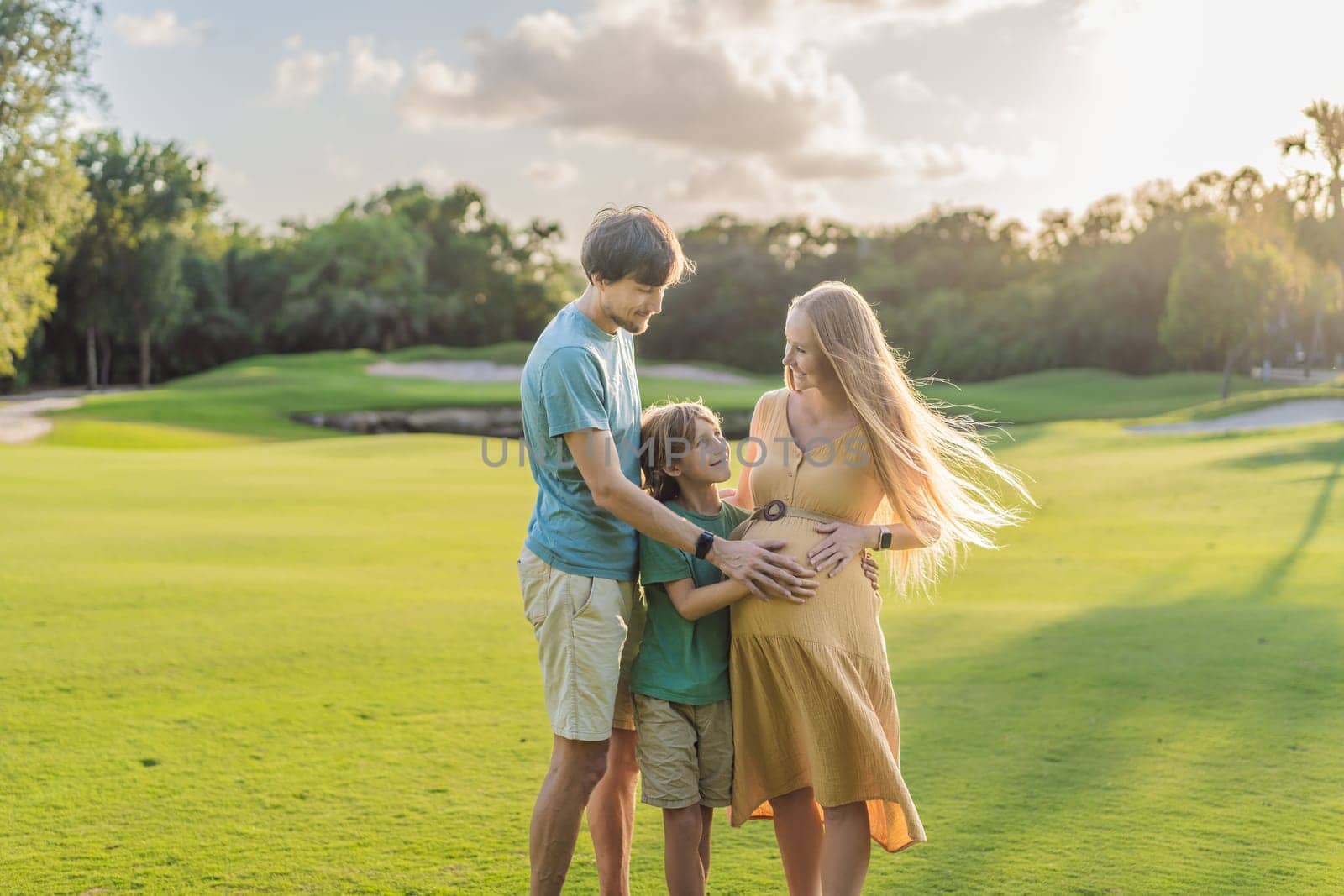 Joyful family time as a pregnant woman, her husband, and son share quality moments outdoors, embracing the beauty of nature and creating cherished memories together.