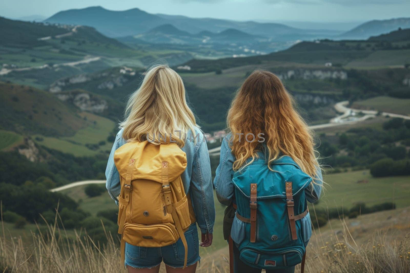 Rear view of two female friends backpackers looking at breathtaking views across the hills in the north of Spain.