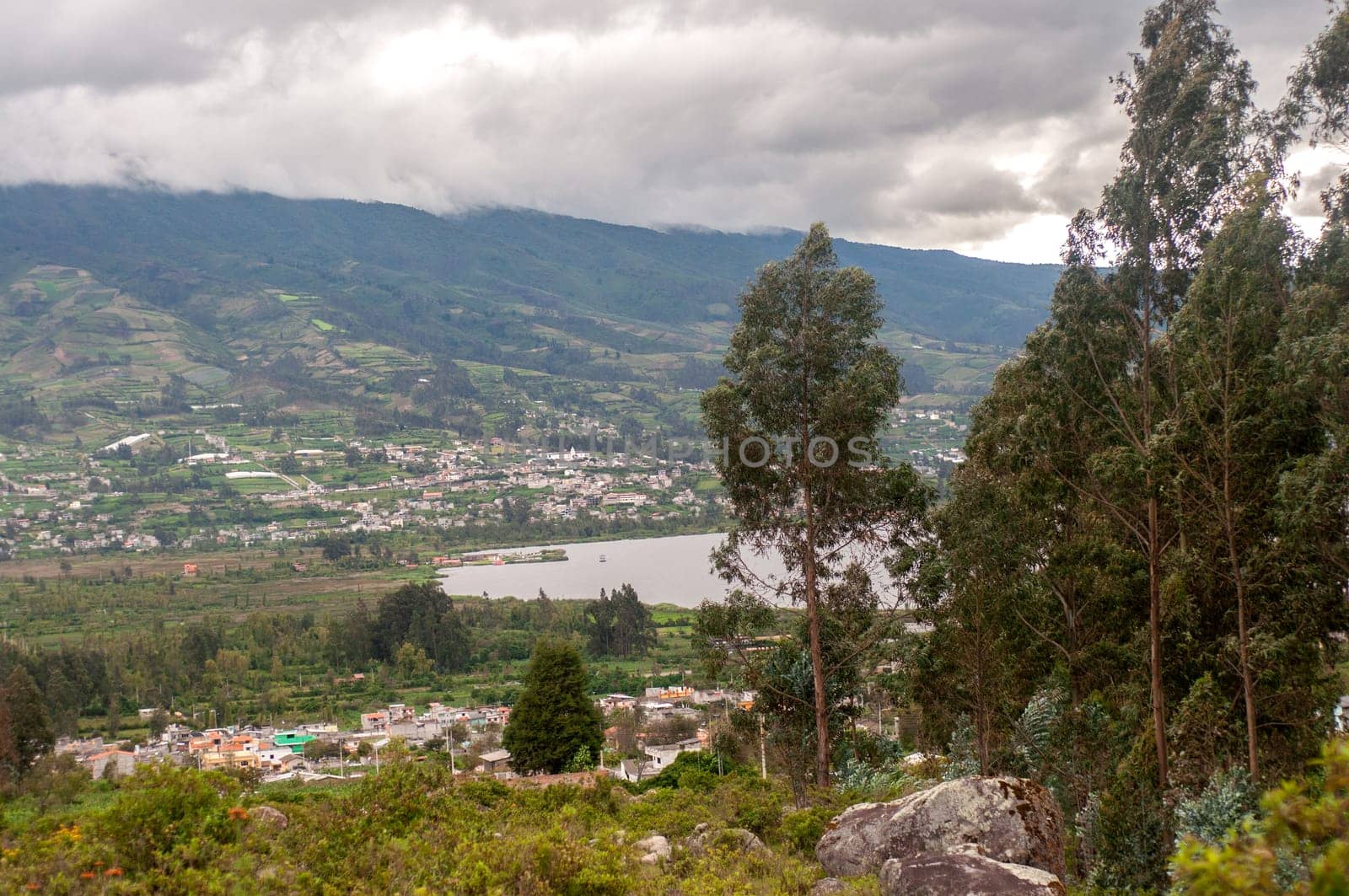 This photo captures a birds-eye view of a town and lake in Ecuador, offering a panoramic perspective of the landscape.