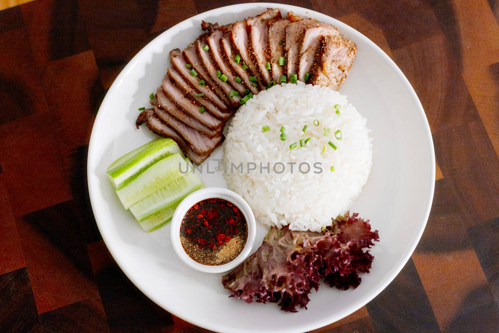 Grilled Beef With Dipping Sauce In White Dish On Wooden Background. Grilled Beef with cooked rice and spicy sauce.

