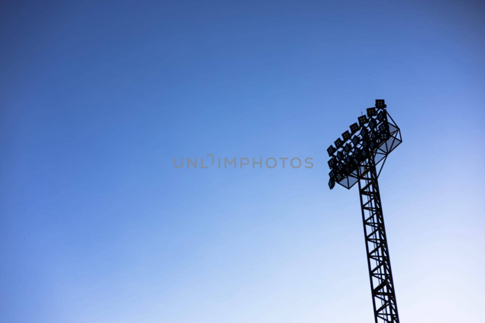 Spotlights to illuminate the stadium. Stadium floodlight with metal pole with blue sky in the football stadium.