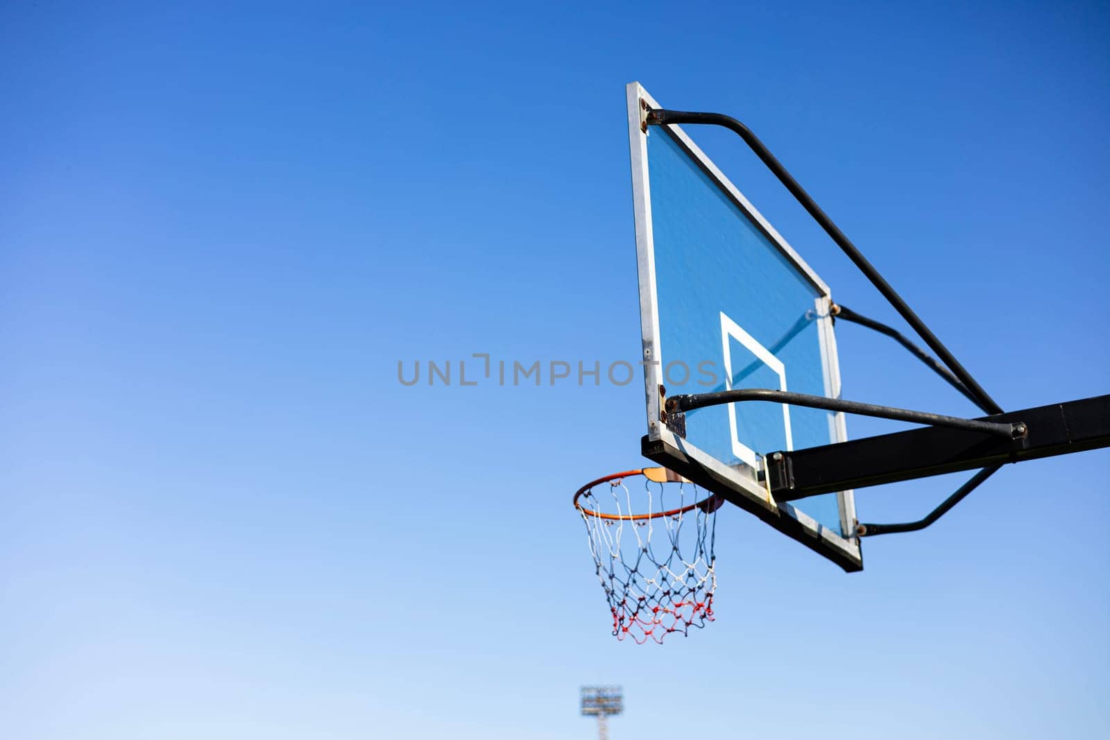 Outdoor Basketball hoop with blue sky background in the public arena.