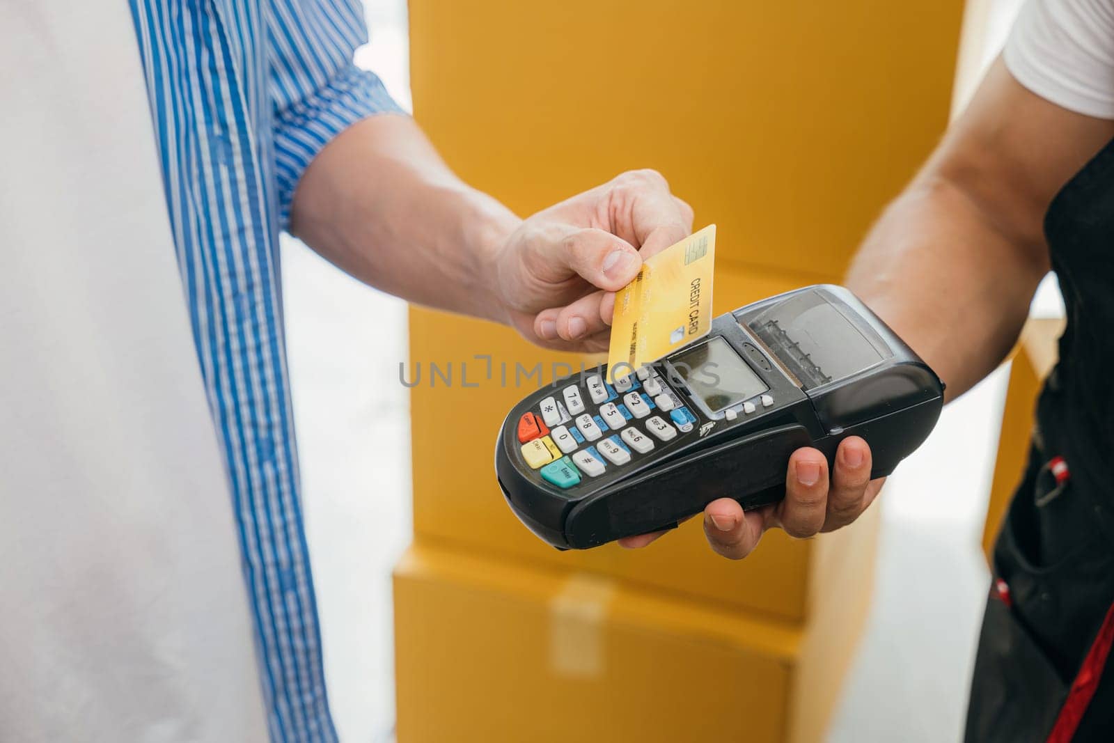 Family completes the move paying via credit card. Worker holds a box. Professional movers ensure efficient home relocation. Teamwork and service shown. Moving Day Concept