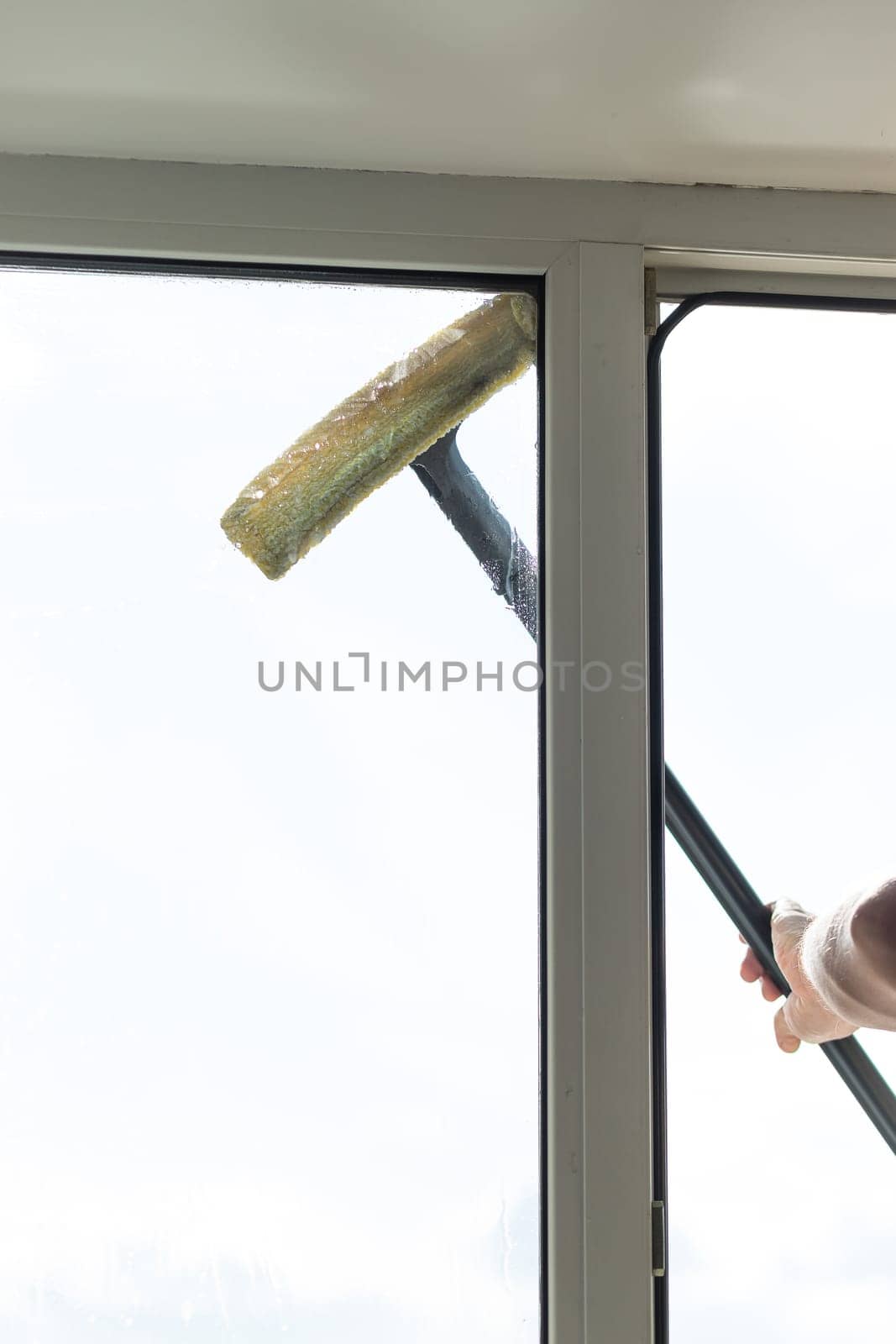people, housework and housekeeping concept.cleaning window glass with sponge mop and foam.special brush, cleaning large open window . by YuliaYaspe1979