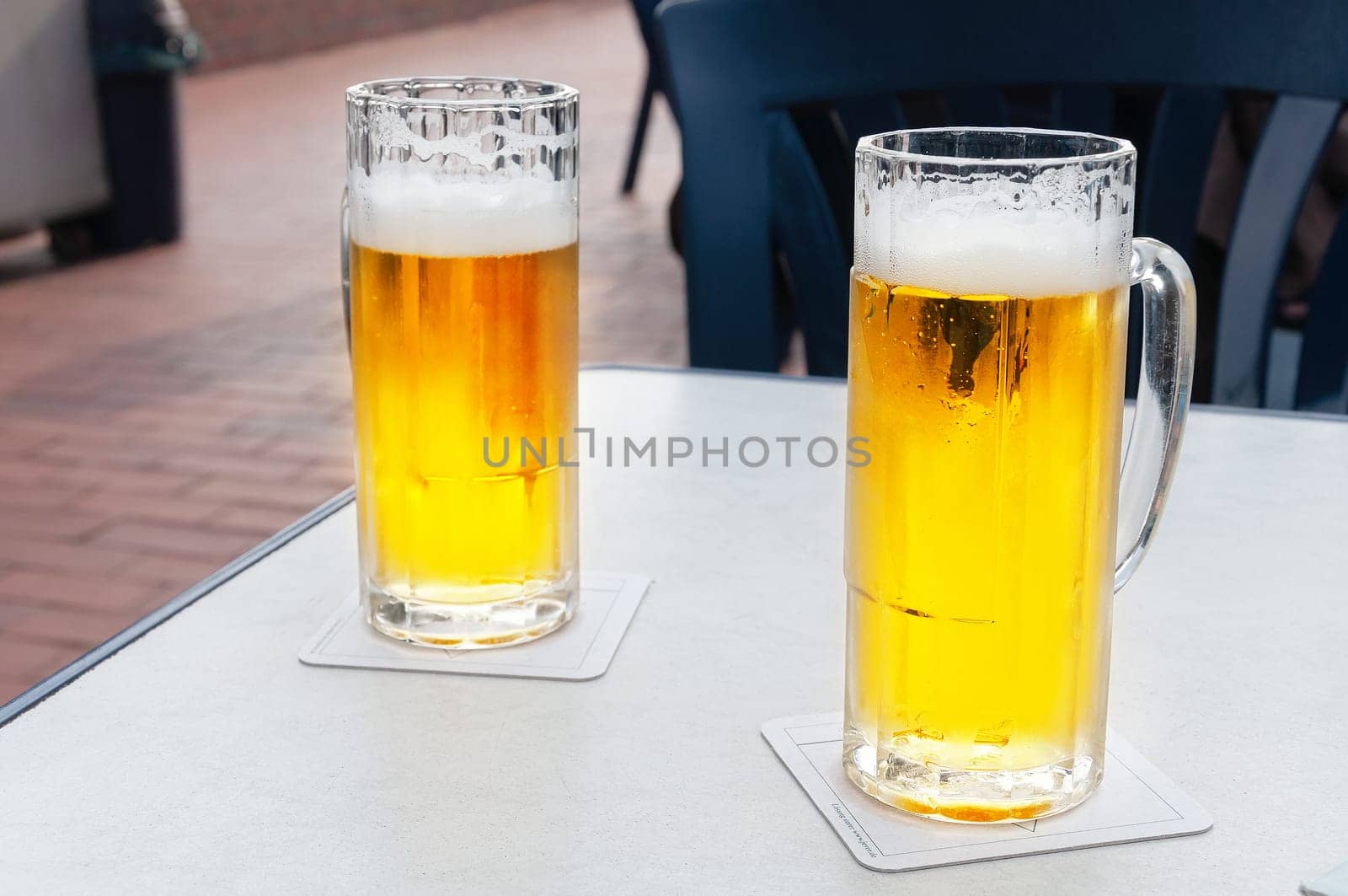 Glasses of cold beer on white table.