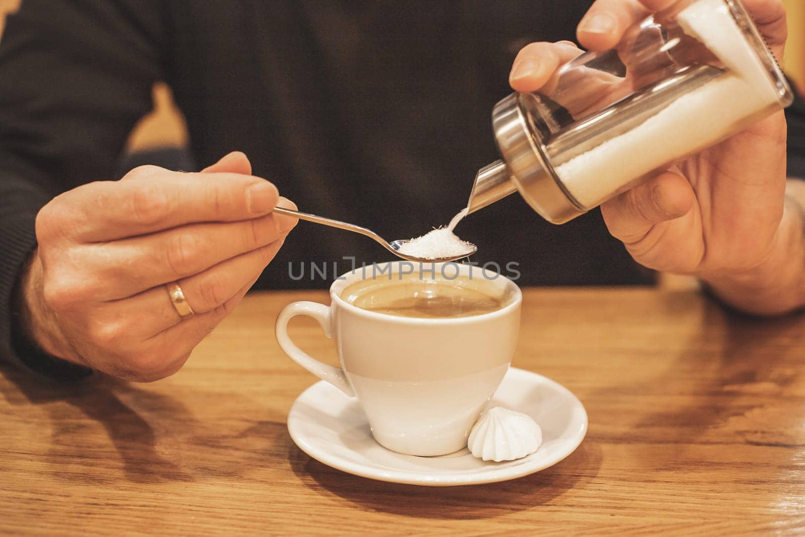 close-up of a businessman's hand with coffee in a cafe, pour sugar to spoon, into a cup of espresso, morning coffee concept.Coffee brake. Morning habit. by YuliaYaspe1979