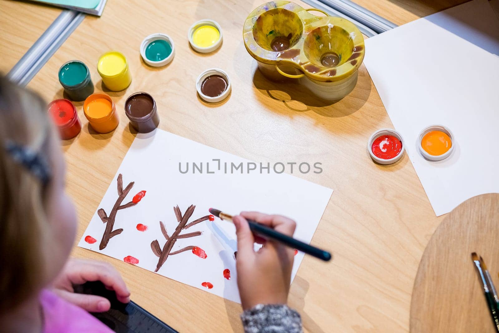 Child drawing picture with crayon in album using a lot of painting tools. Creativity concept.
