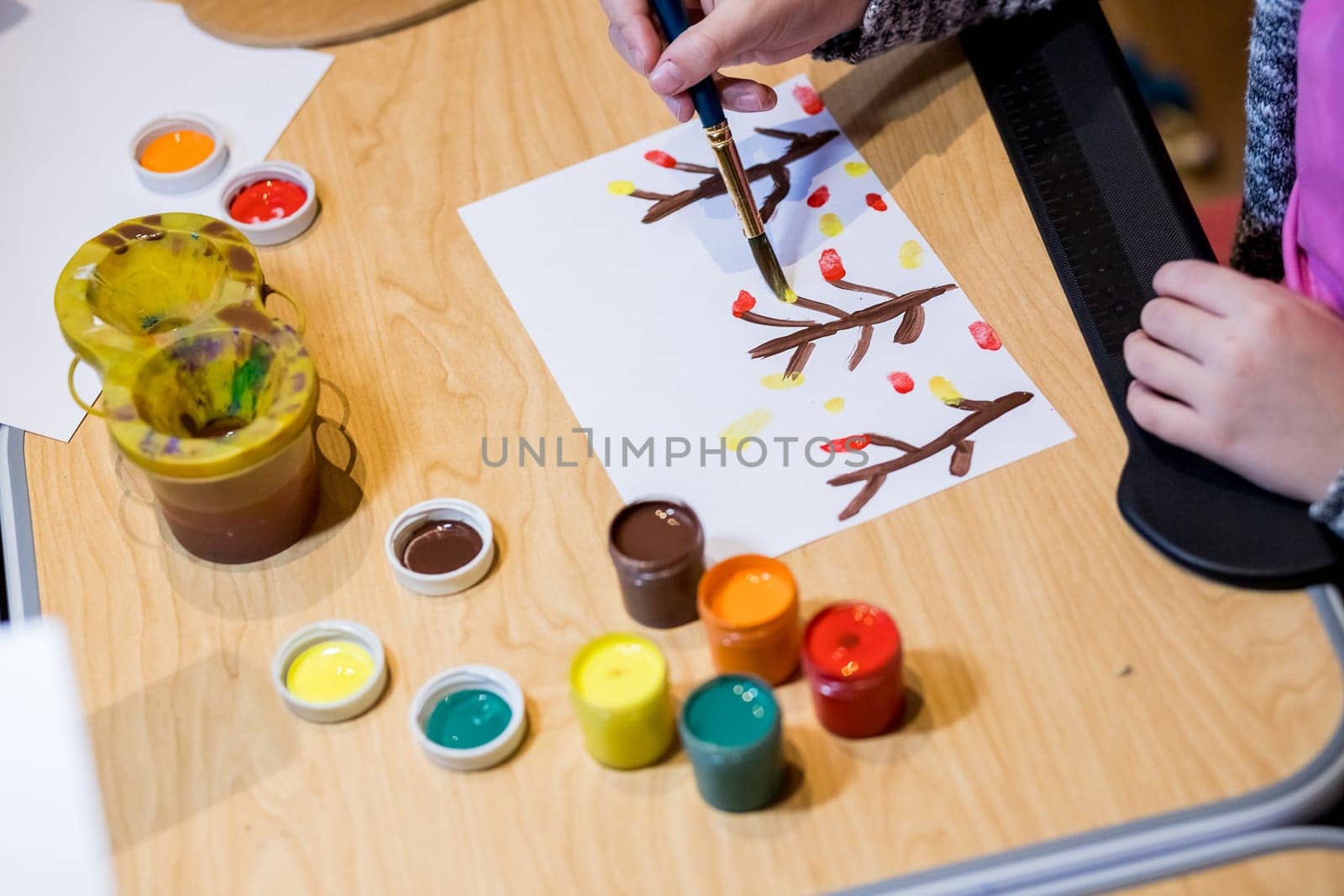 Child drawing picture with crayon in album using a lot of painting tools. Creativity concept.