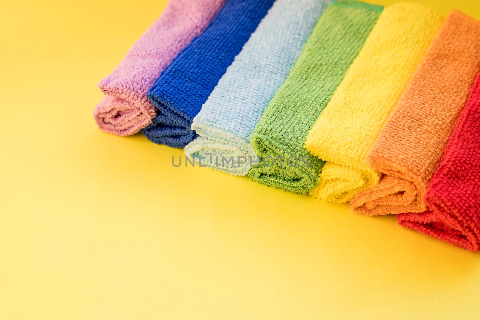 colorful microfiber towels, over yellow background.Cleaning microfiber cloth isolated , Folded cleaning textile napkins colorful stack. Domestic household cleaning service concept.Copy space by YuliaYaspe1979