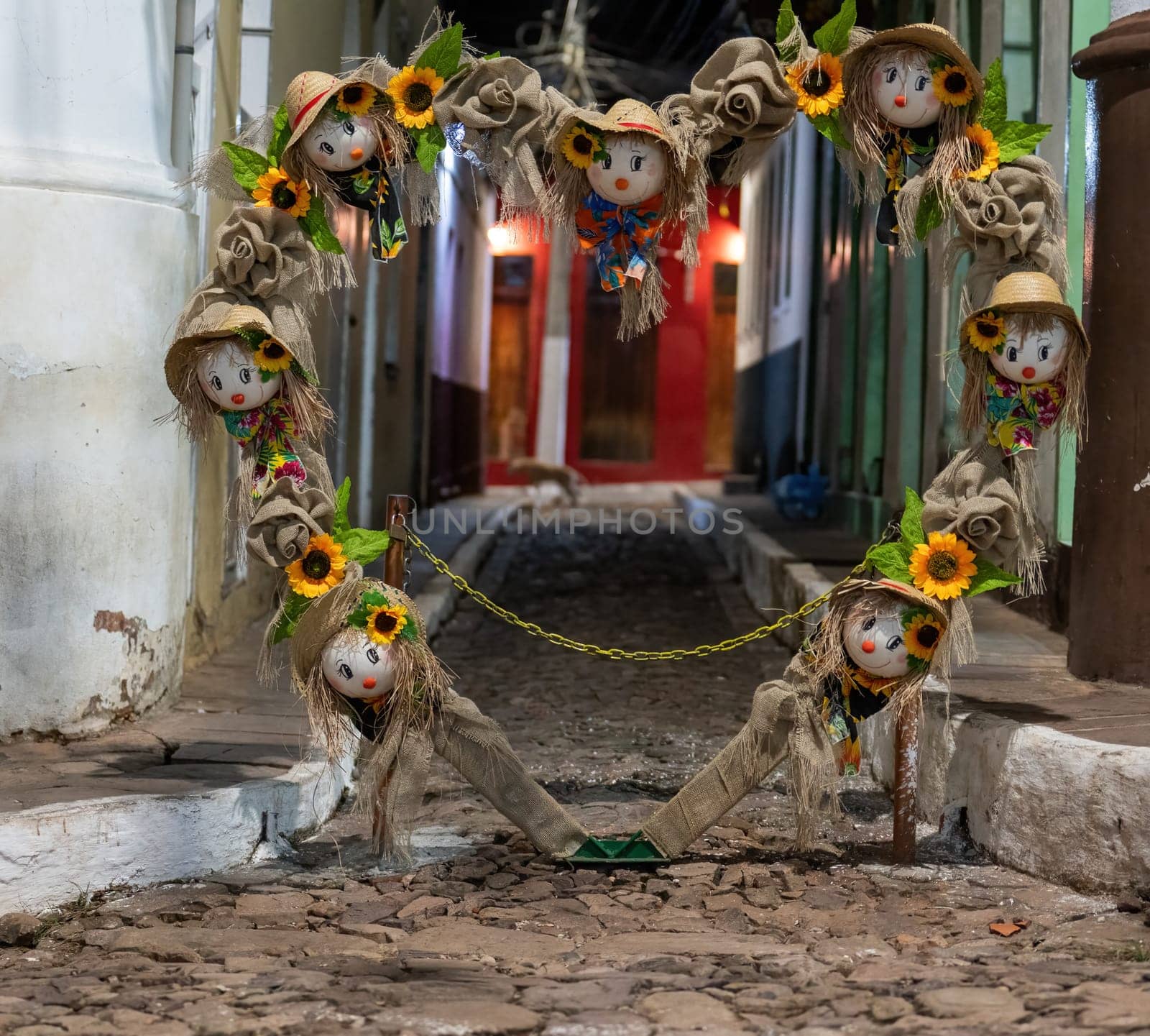 Decorative scarecrows hanging over a cobblestone alley by FerradalFCG