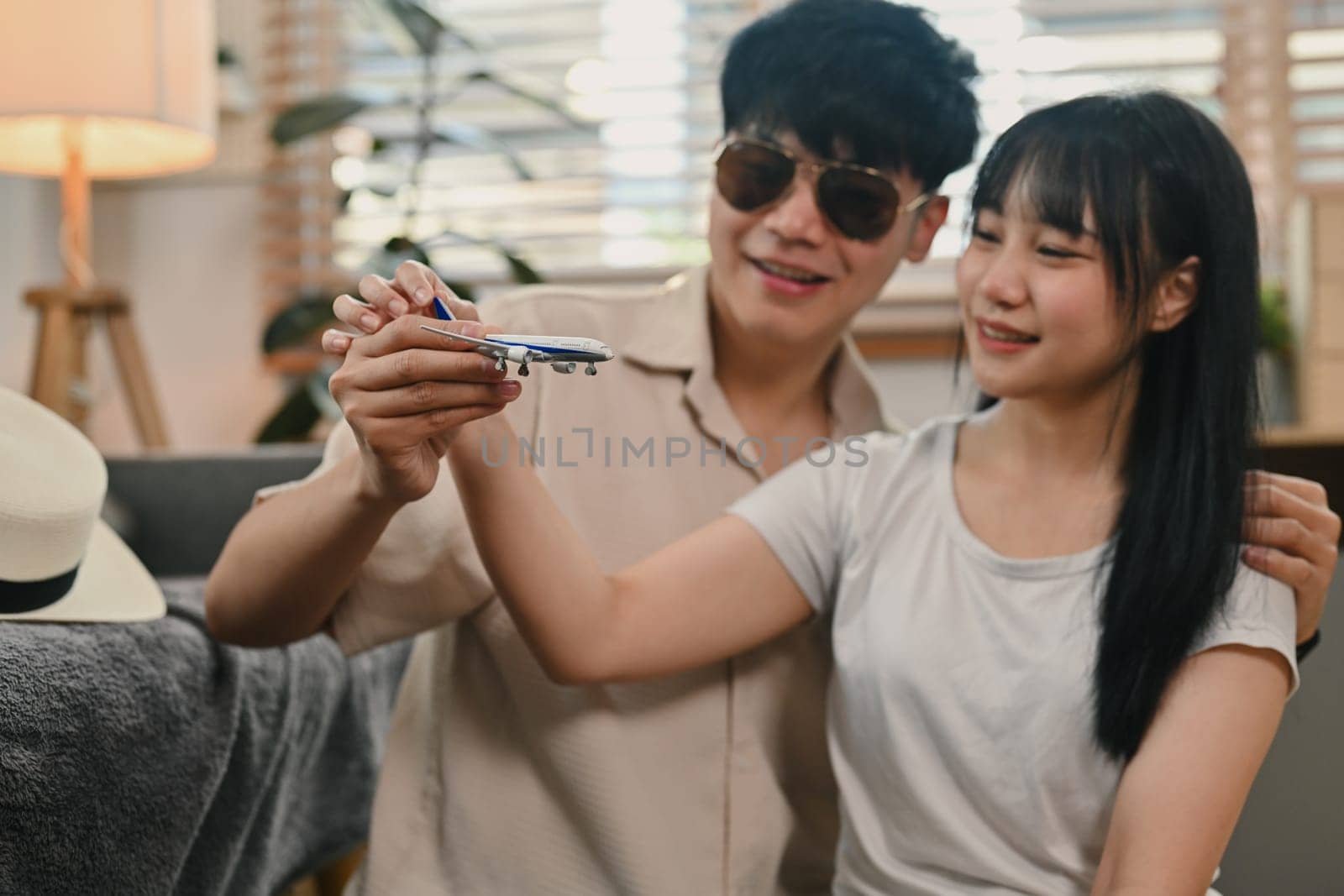 Beautiful couple holding airplane model. Traveling, vacation and transportation concept by prathanchorruangsak