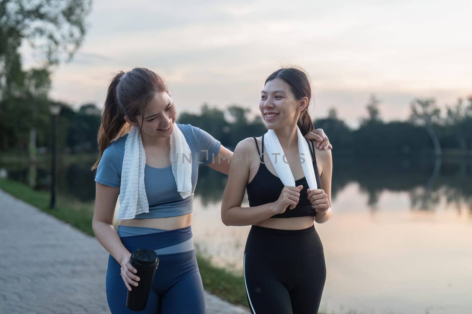 Two happy women going for sunrise running. Women in track suits running at park.