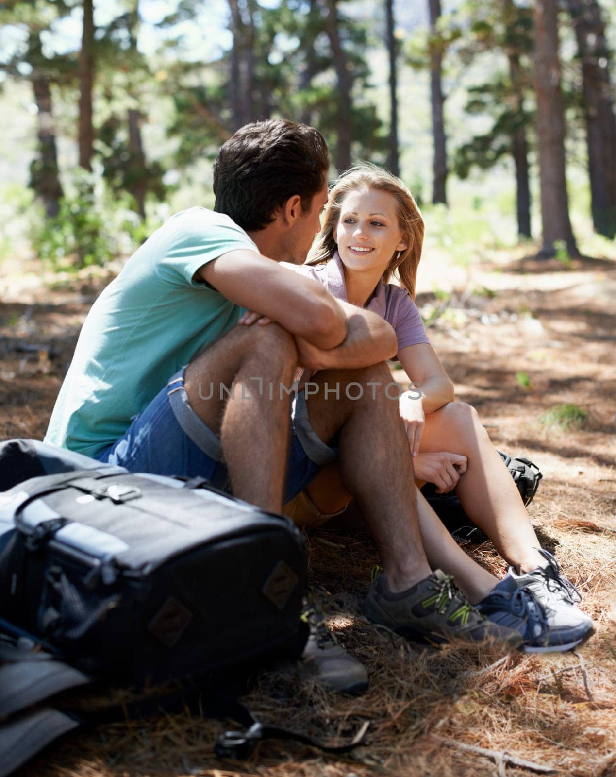 Couple, hiking break and travel in forest for outdoor fitness, adventure and wellness journey or health in nature. Happy man and woman relax on ground or talking of trekking destination with backpack.