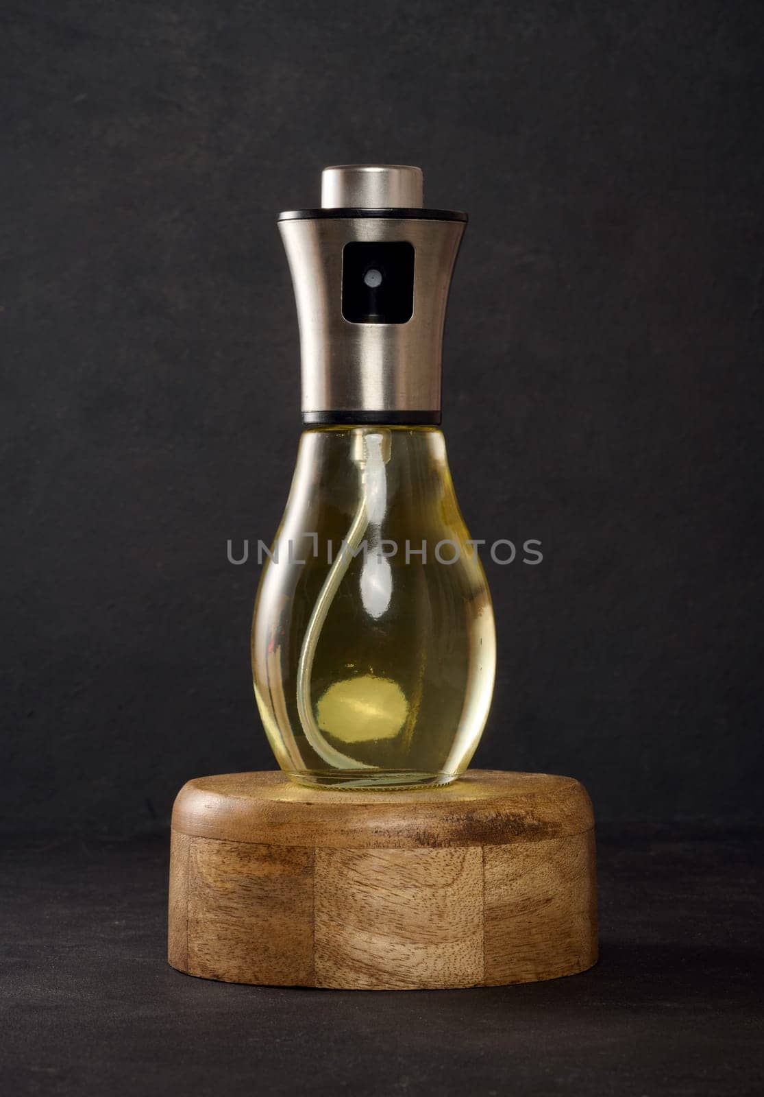 Glass transparent spray bottle filled with sunflower oil on a black table
