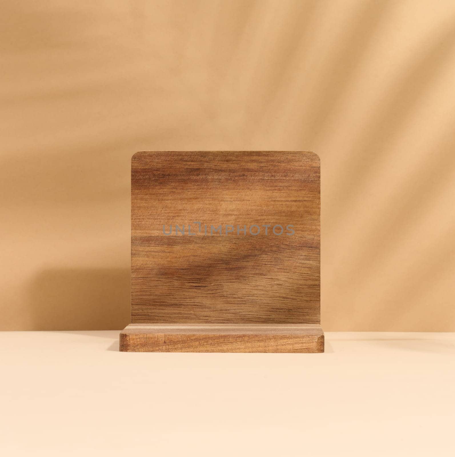 Wooden platform, shadow from a palm leaf on a brown background. Place for displaying cosmetics by ndanko