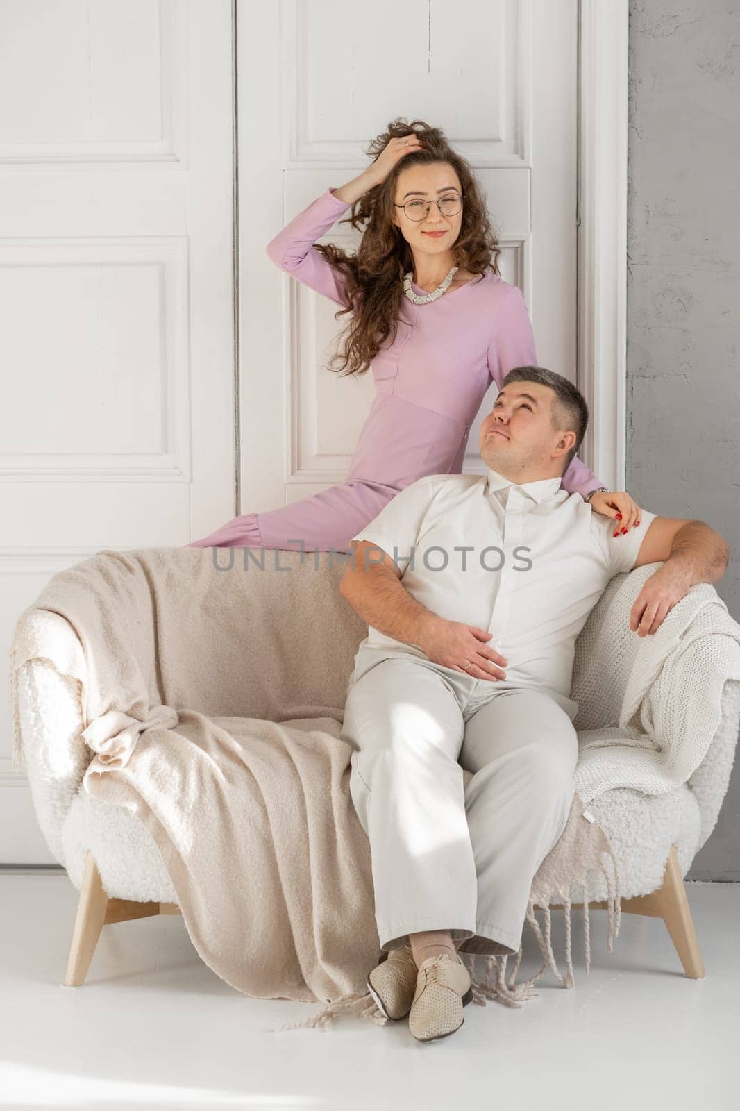 Young happy couple sitting on a sofa in a large studio. by AnatoliiFoto