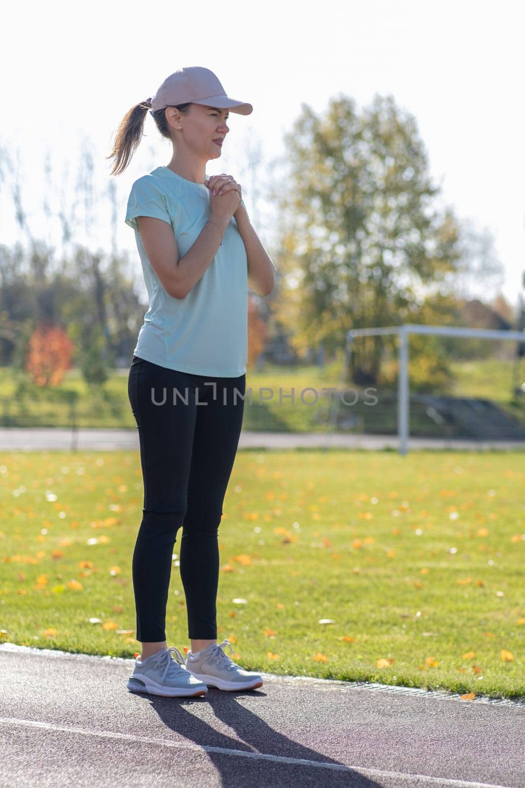 A young beautiful woman in sportswear plays sports at a local stadium by AnatoliiFoto