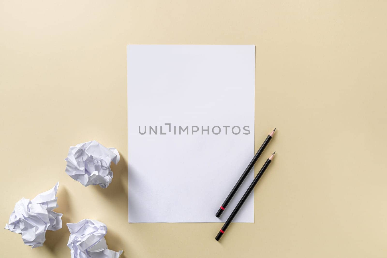 Blank writing sheet with pen and crumpled paper balls lay flat on yellow background