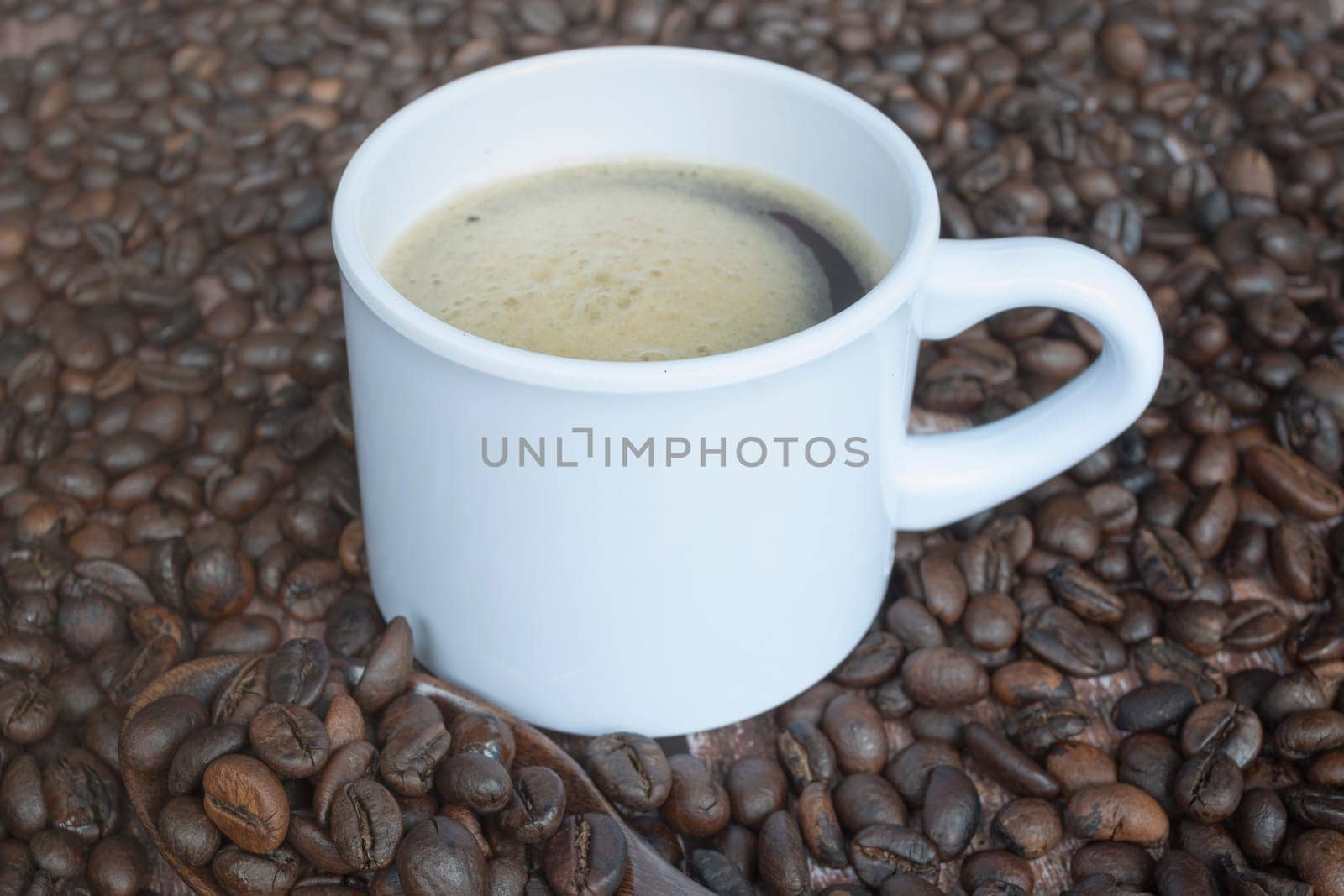 Fresh roasted coffee bean background with a cup of hot espresso. Copy space.