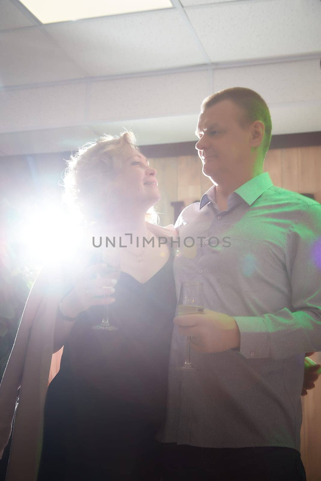 Adult man and woman are conversing on stage in a dimly lit room before a performance or interview. The actors, actress, host, journalist, and paparazzi capturing their intimate, secretive conversation by keleny