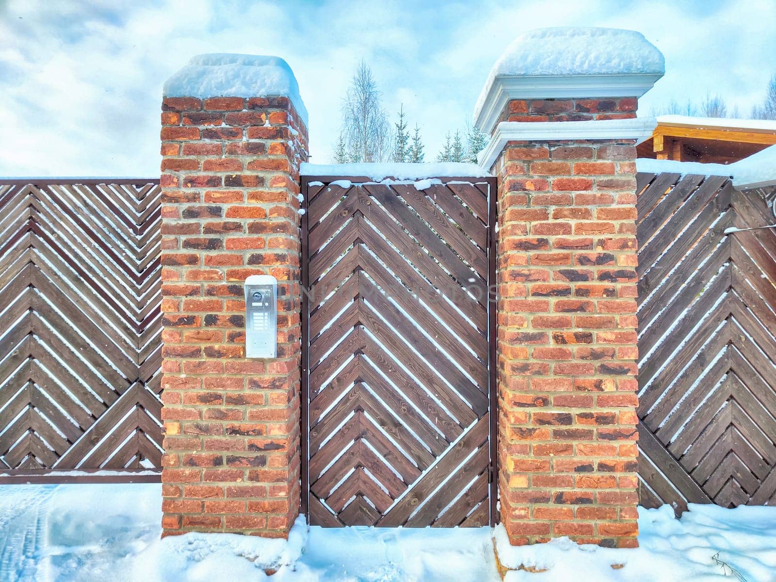 New gate, entrance to a private territory on a winter day and snow. Metallic texture and background. Fence