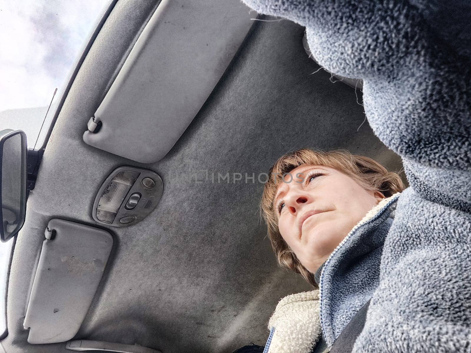 Portrait of female driver in solo journey. Adult mature woman holding steering wheel and looking through windscreen in travel by vehicle on vacation. Lady girl who is owner or rent car for travel