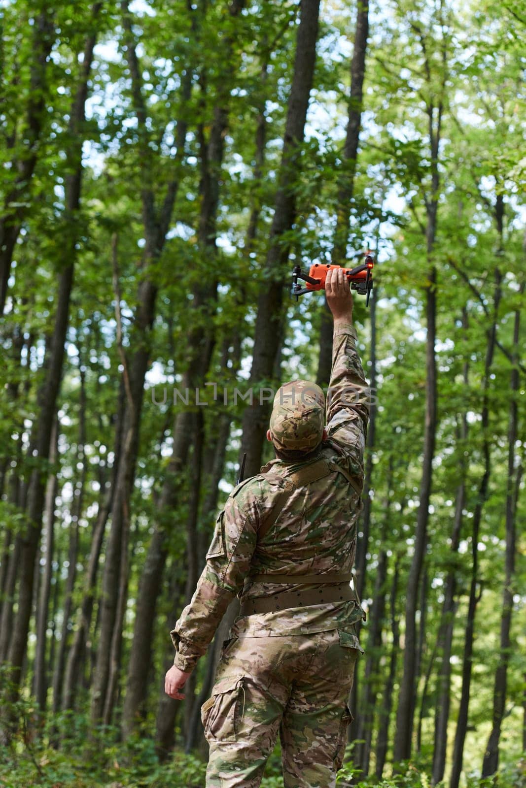 Elite military unit, equipped with state-of-the-art technology including a drone, strategically navigates and surveys dangerous wooded terrain, showcasing their precision, cooperation, and specialized training for high-risk operations.