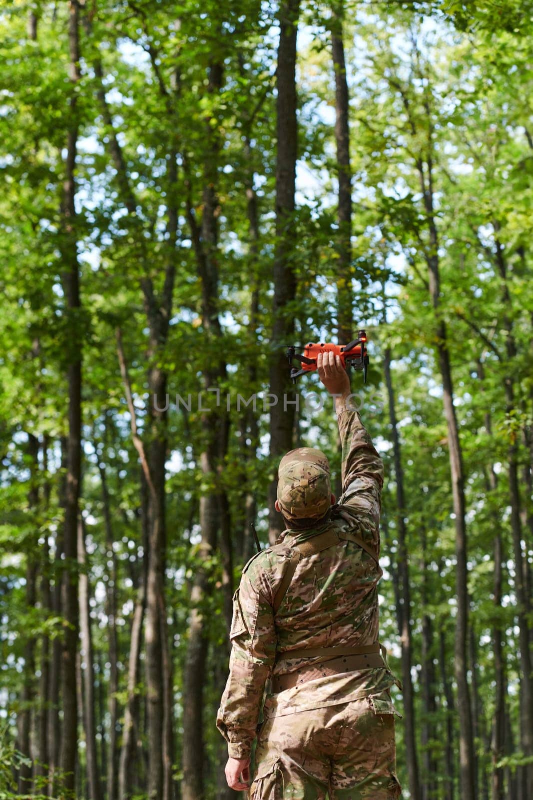 Elite military unit, equipped with state-of-the-art technology including a drone, strategically navigates and surveys dangerous wooded terrain, showcasing their precision, cooperation, and specialized training for high-risk operations.