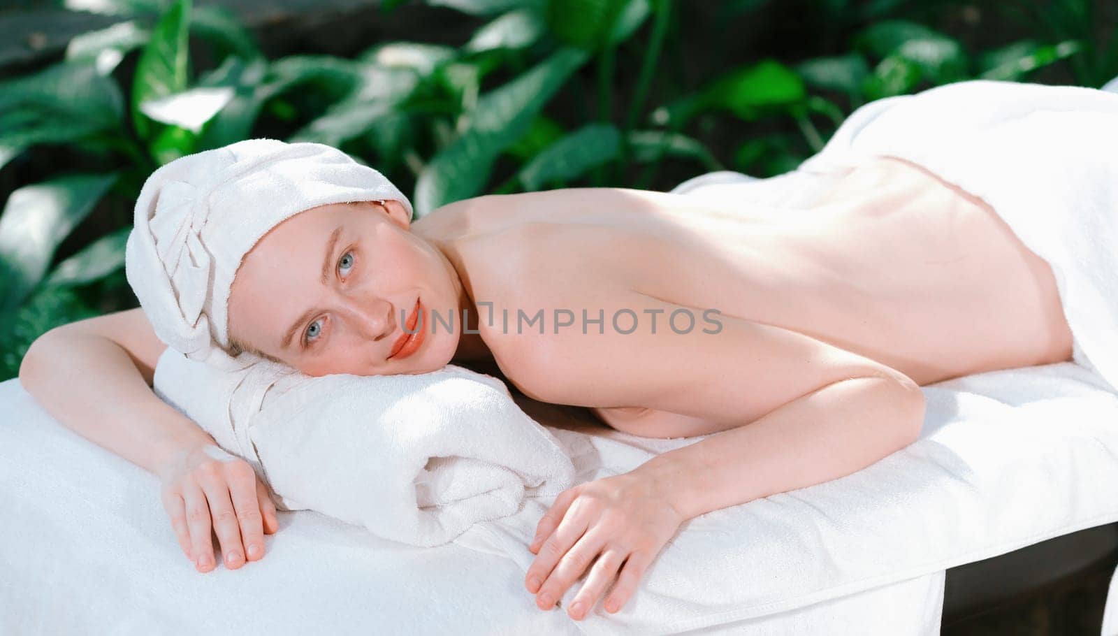 Beautiful woman relaxes on a spa bed while looking at camera. Tranquility by biancoblue