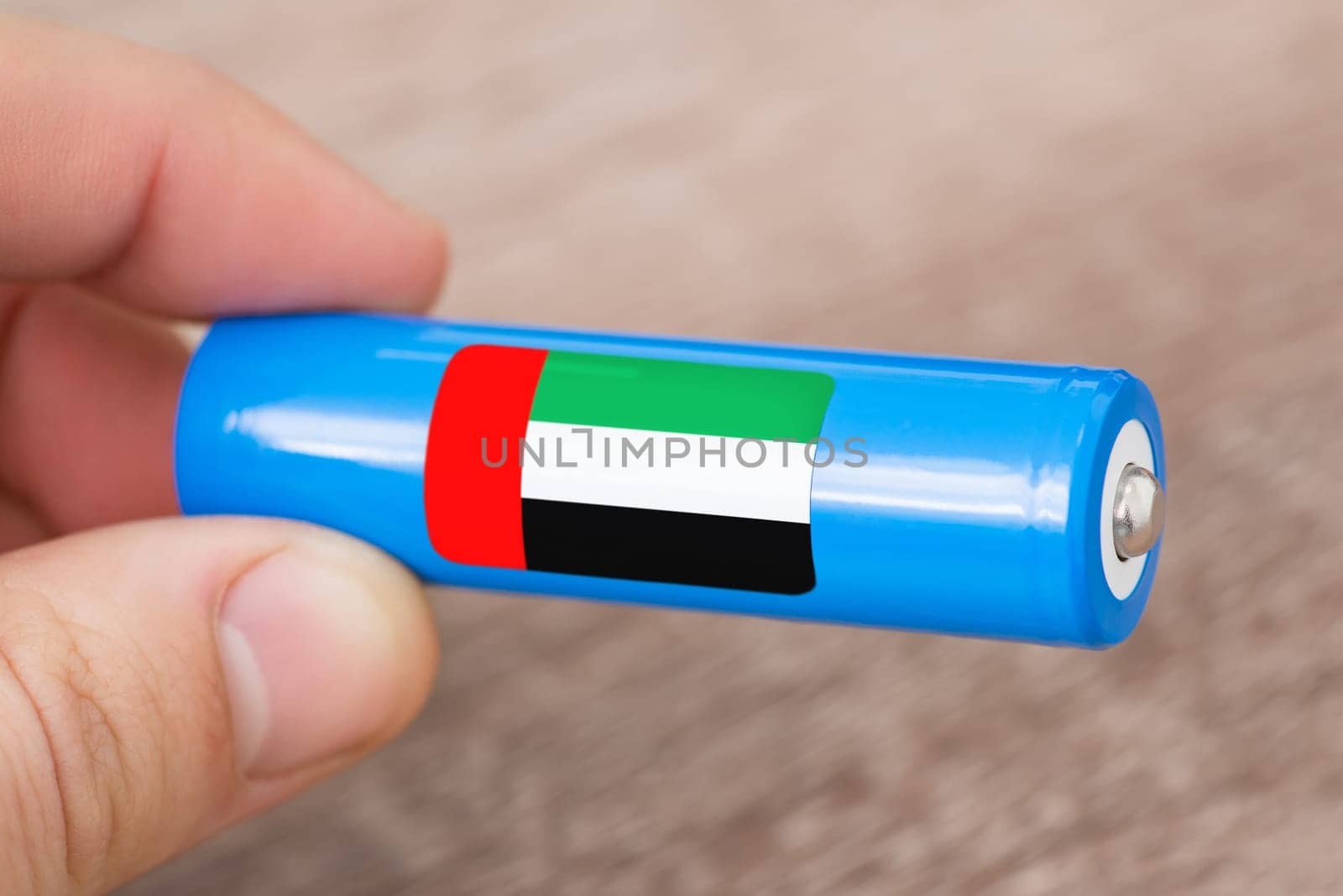 Rechargeable battery with flag of United Arab Emirates in hand of a man by VitaliiPetrushenko