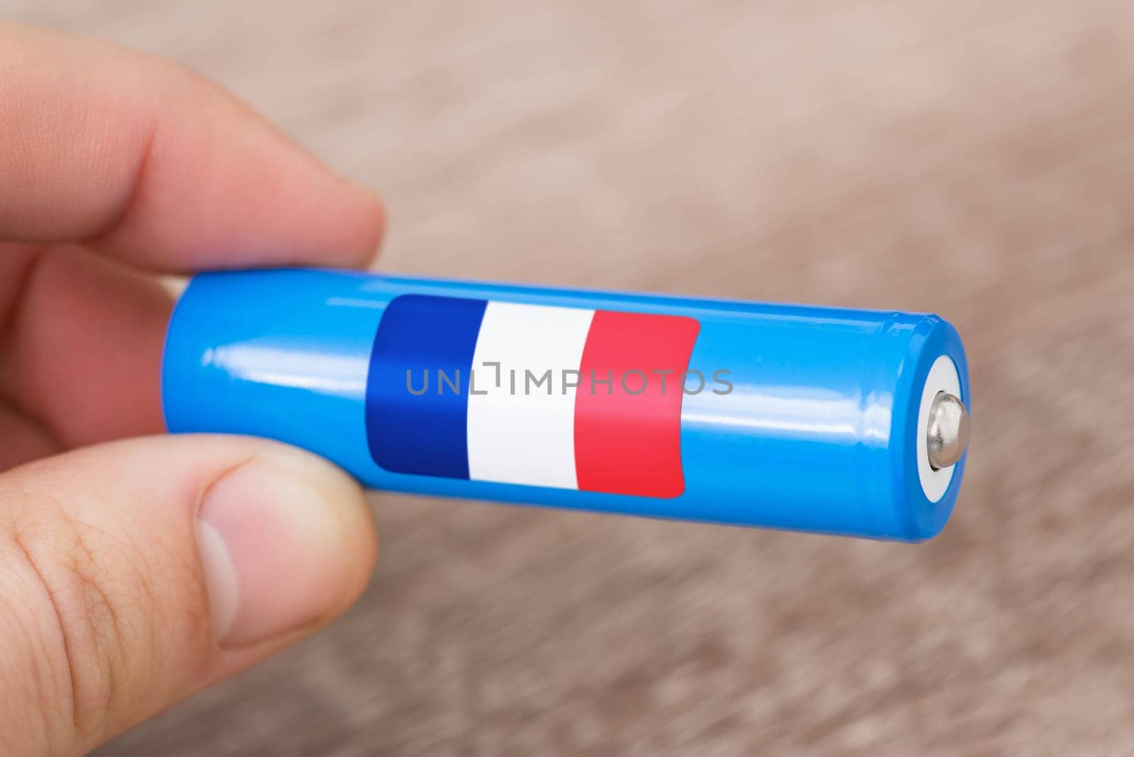 Rechargeable battery with flag of France in hand of a man by VitaliiPetrushenko